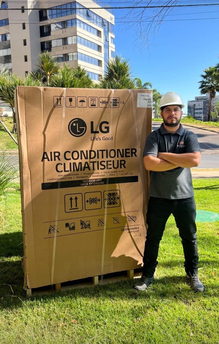 Engenheiro da SC Soluções Engenharia com capacete ao lado de equipamento de ar-condicionado